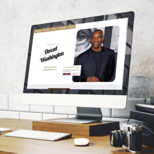 Website-Mockup auf einem iMac. Im rechten Drittel ist ein großes Porträt von Denzel Washington zu sehen, links daneben ist sein Name illustriert. Oben befindet sich ein goldener Header, unten in der Mitte eine Cookie-Abfrage.