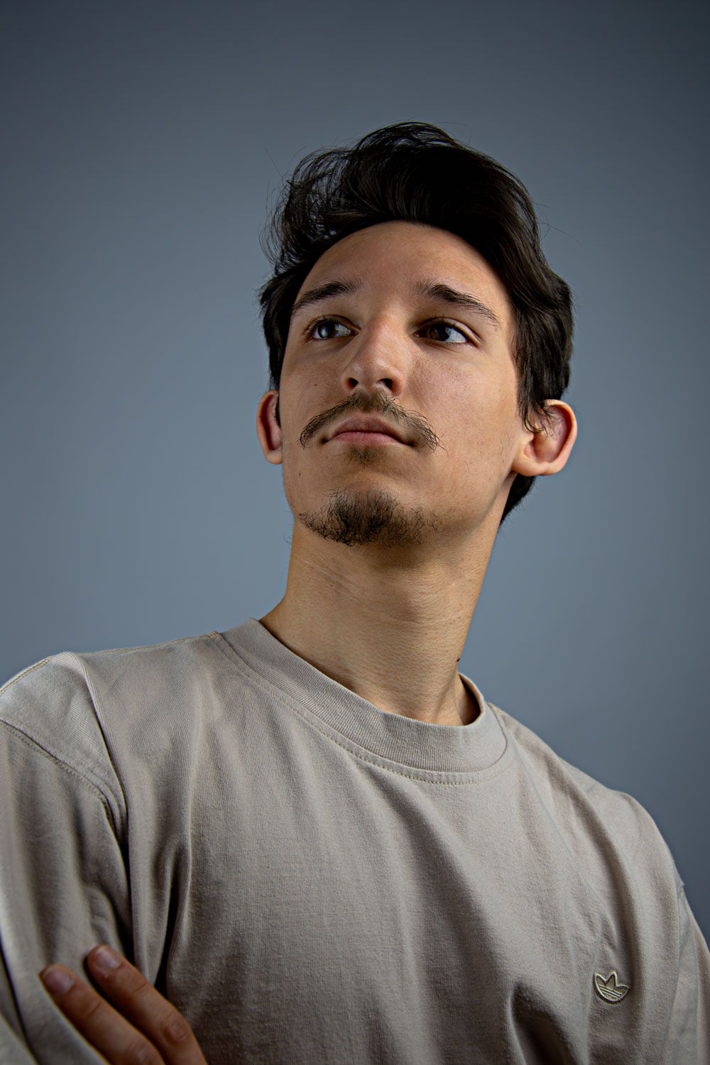 Porträt von Julian mit verschränkten Armen, er blickt nach links oben.