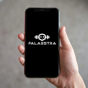 Ein Handy-Mockup mit einem Kombiniertesm Logo. Das Wortzeichen sagt Palaestra, das Bildzeichen ist darüber mit einem Roboter-Mascoutchen Logo, welches Hantel Ohren hat.