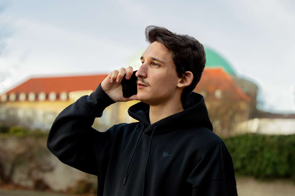 Julian sieht man im Drei-Viertel-Profil, wie er telefoniert.